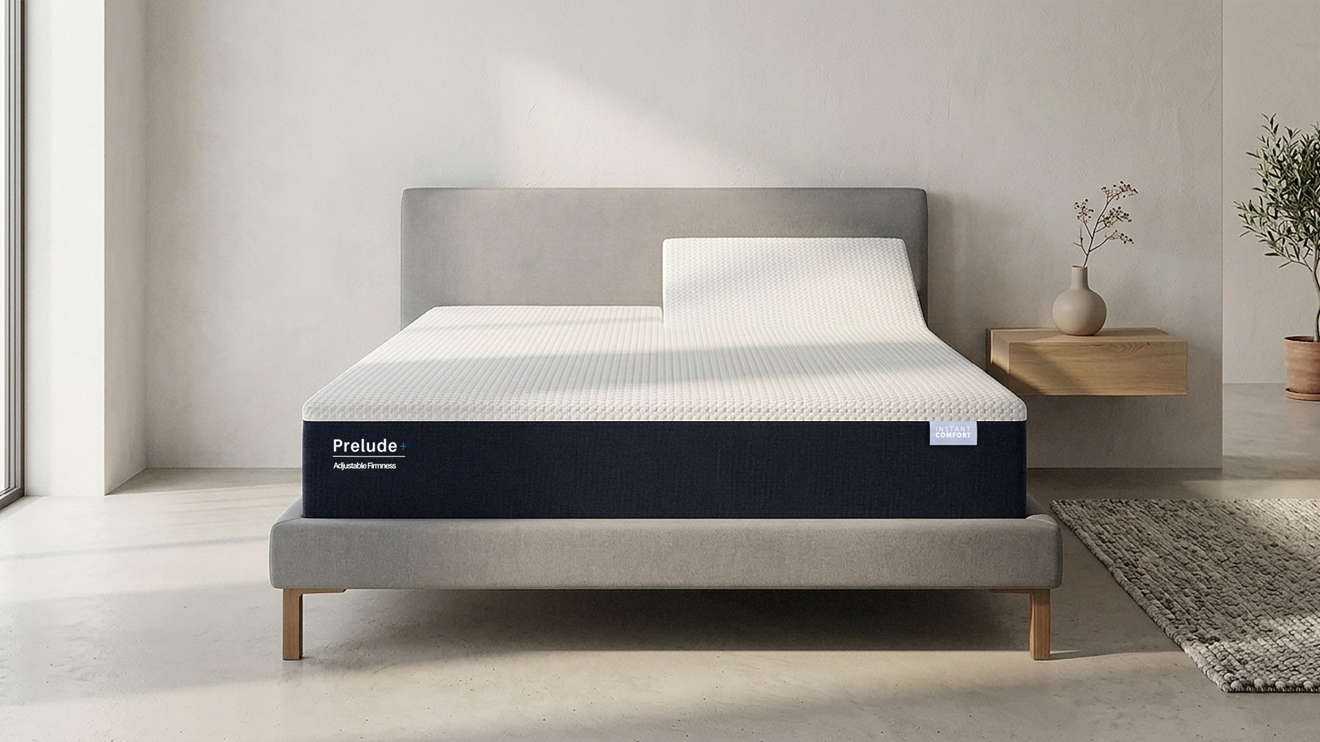 Mattress on a bed in a minimalistic room with a side table and plants.