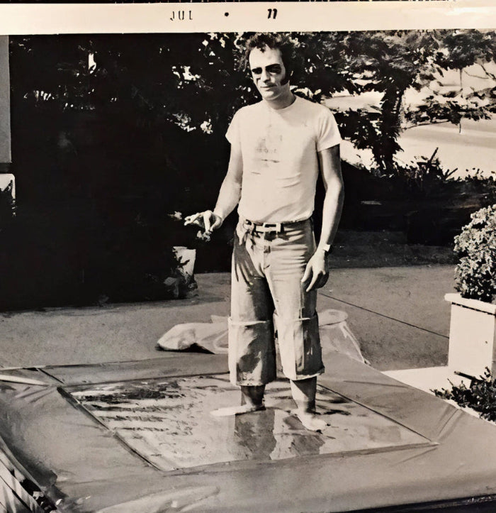 Black and white photo of a person standing on a star-shaped rug outdoors.