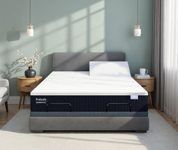 Gray bed frame with white mattress in a room with light green walls and wooden furniture.