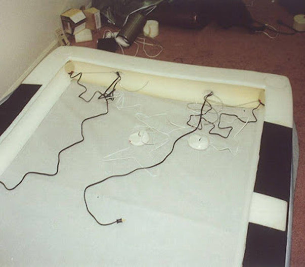 Bed with wires and a lamp on top, possibly indicating an electrical issue or experiment.