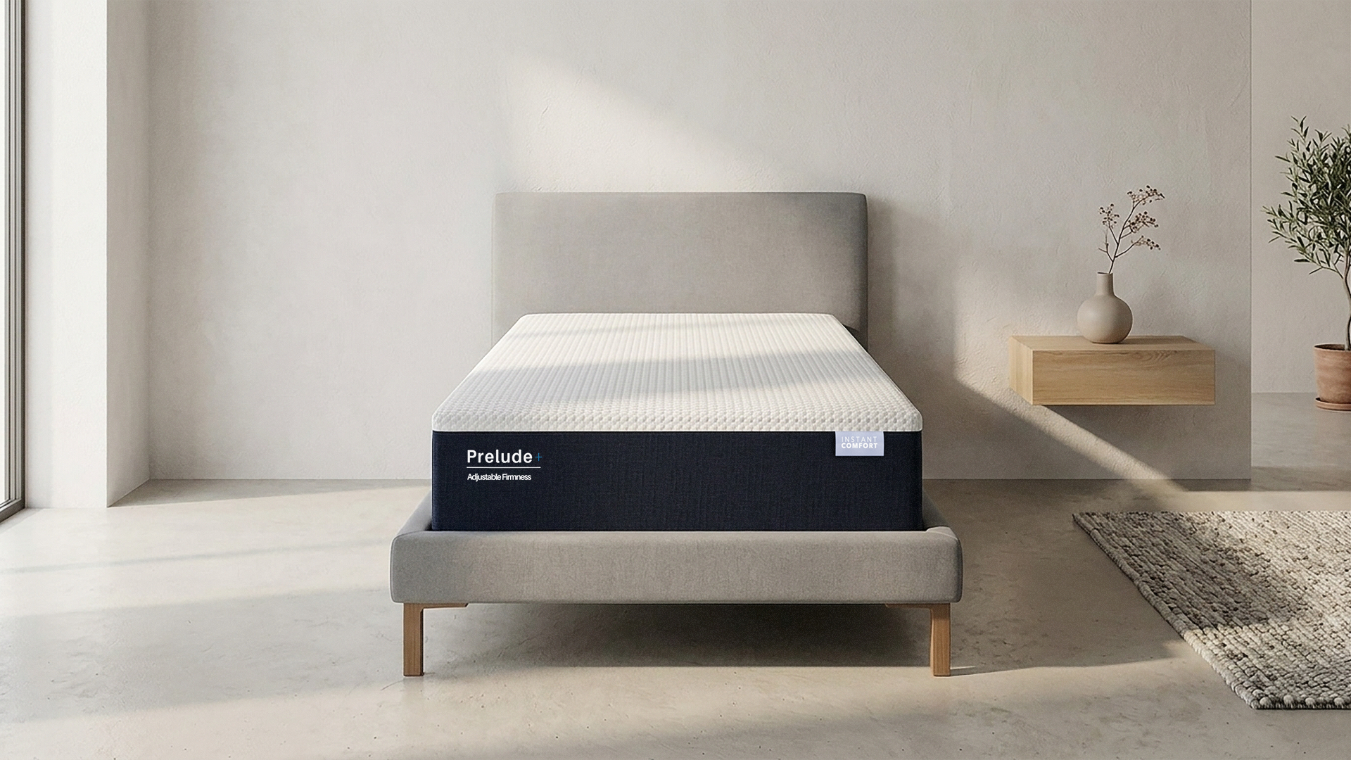 Prelude mattress in a minimalistic room with a side table and plant.