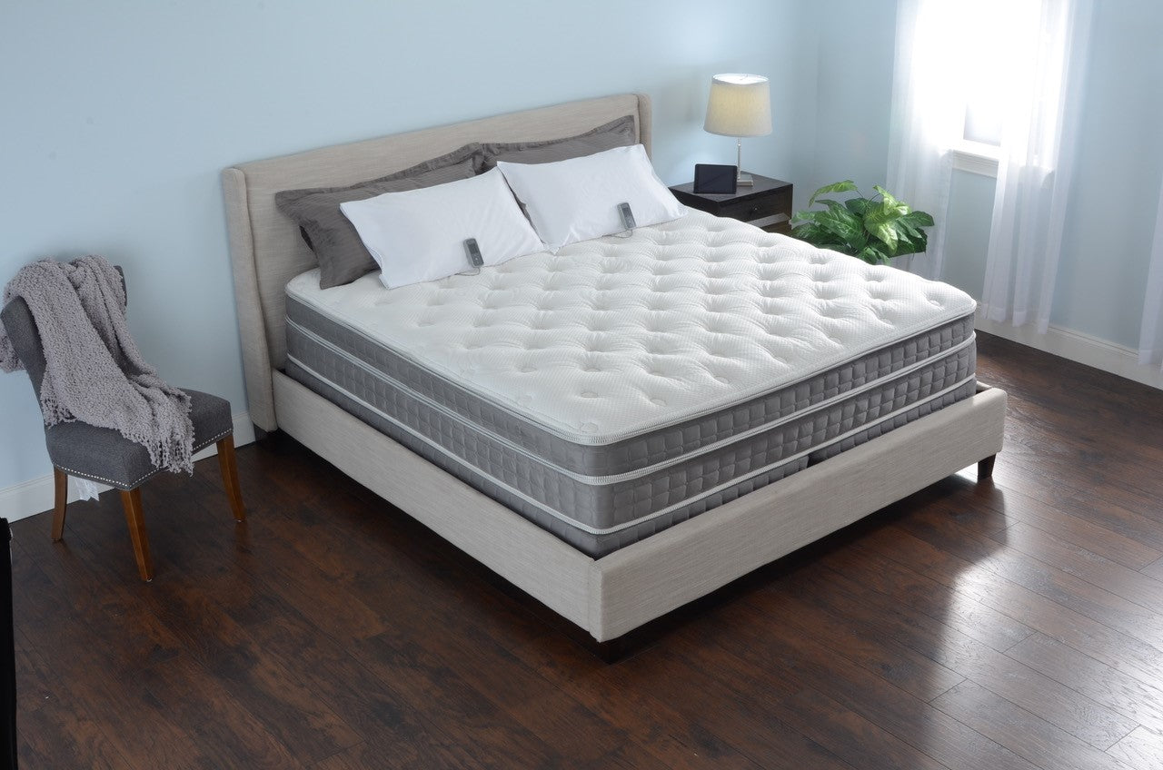Mattress on a bed in a bedroom setting with a chair and lamp.