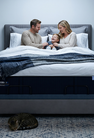 Family of three on a bed with a mattress brand logo visible